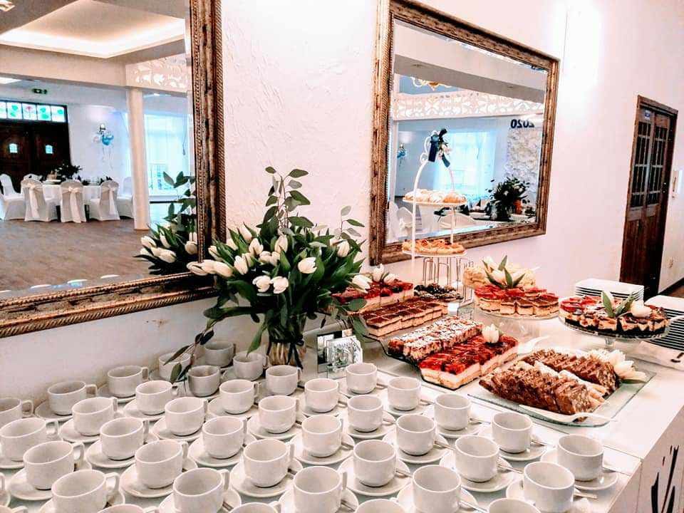 Bufet kawowy z filiżankami i ciastami przy lustrze