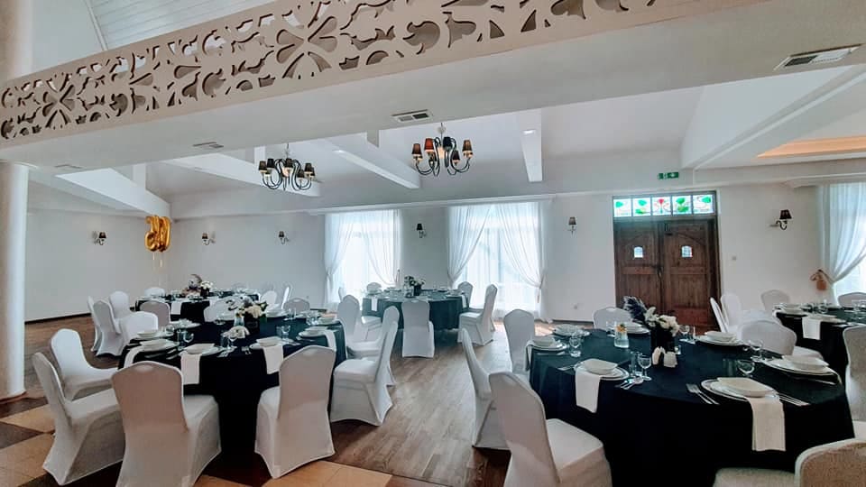 Sala z ażurową balustradą antresoli i nakrytymi stołami